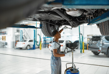 Wall Mural - Male mechanic drains the oil, car service