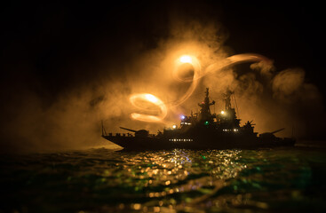 Silhouettes of a crowd standing at blurred military war ship on foggy background. Selective focus.