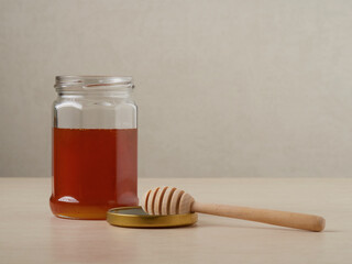 Wall Mural - Honey dripping from a wooden dipper in jar on old cutting board on white wooden rustic background close up. Selective soft focus. Text copy space.