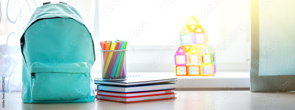 Banner. Concept back to school. Full turquoise School Backpack with stationery on table. - obrazy, fototapety, plakaty 