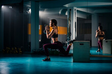 A Young Fit Woman Doing Split Squats Exercise In Gym