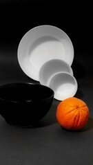 Wall Mural - White and black dishes in the background and orange in front