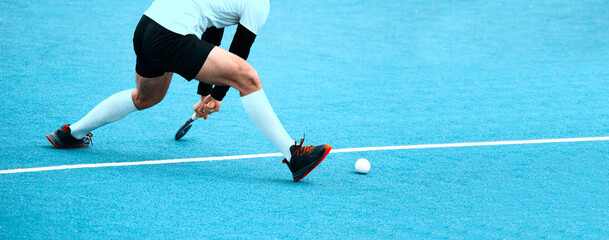 Young hockey player man with ball in attack playing field hockey game. Vintage color filter