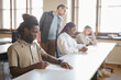 © Seventyfour - Diverse group of students taking exam in college while sitting in row at desk in auditorium, focus on young African-American man in foreground, copy space