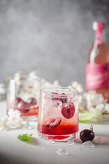 Wall Mural - Cold cherry lemonade drink with fresh cherry and ice on gray background