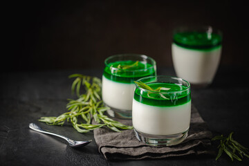 Wall Mural - Dessert Panna Cotta with green tarragon sauce and fresh tarragon on dark background