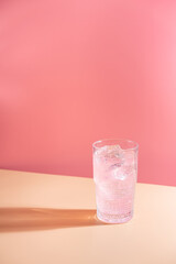 Wall Mural - Summer refreshment pink drink with ice. Light pink rose cocktail on a pink background with bright shadows