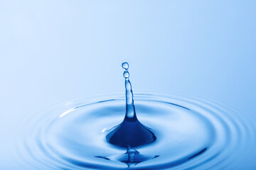 Wall Mural - Drop of water. Water droplet falling impact with water surface. causing rings on water surface..