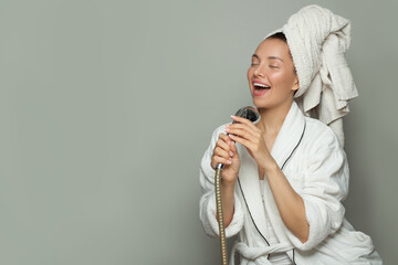 Happy excited spa model woman taking a shower and singing on gray background