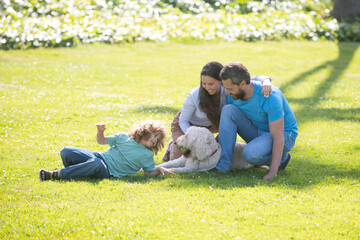 Wall Mural - Beautiful happy family is having fun with dog outdoors. Cute family portrait. The concept of a happy family.