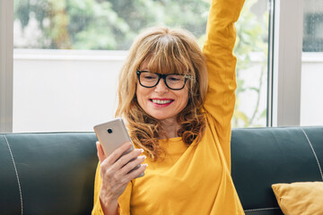 woman looking at mobile phone with arm raised triumphant