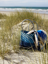 Bag And Towel Sitting On Grassy Sand Dune At The Beach