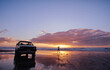 © SuperStock - White Ute parked on the beach and lone person standing by the water at sunset