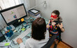 © David Pereiras - Top view of woman working from home with her daughter interrupting her. Selective focus on girl in background