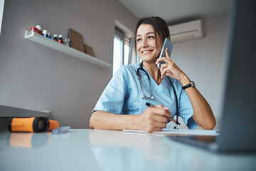 Wall Mural - Charming female doctor having phone conversation at work