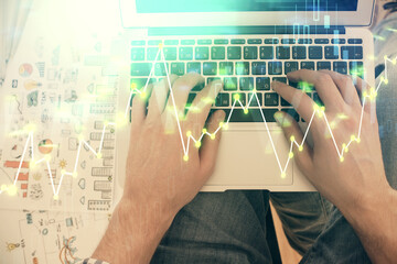 Double exposure of man's hands typing over laptop keyboard and forex chart hologram drawing. Top view. Financial markets concept.