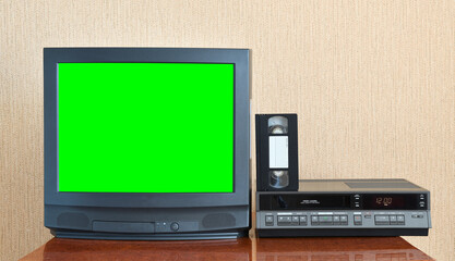 Old black vintage green screen TV from 1980s 1990s 2000s for adding new images to the screen, VCR in the background of wallpaper.