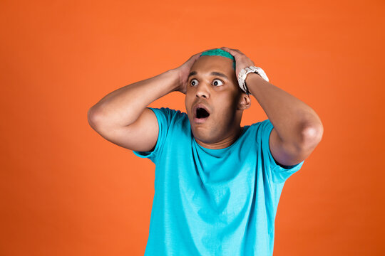 Black african man in casual on orange background blue hair shocked afraid and scared looking to camera with open mouth