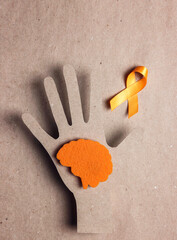 Wall Mural - World Multiple Sclerosis Day. Orange awareness ribbon with hand silhouette and brain symbol on a brown background.