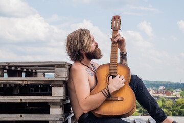 handsome bearded guy with stylish hair playing acoustic guitar, string instrument