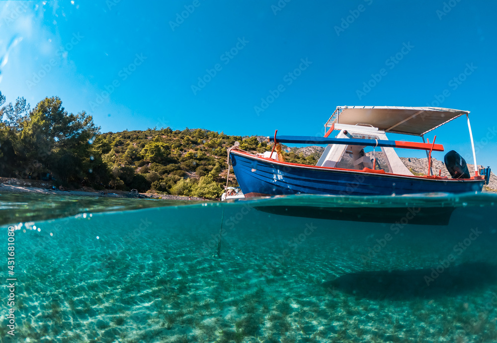 Half underwater photo of a boat in a beautiful beach of Samos island - obrazy, fototapety, plakaty 