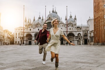 couple of tourists visiting venice, italy - boyfriend and girlfriend in love running together on cit