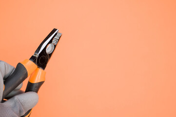 Sticker - Closeup shot of a hand holding pliers with gloves on a colorful background