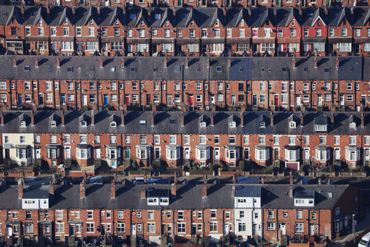 an aerial view taken from a helicopter of suburban terraced streets and roads in britain. many brick