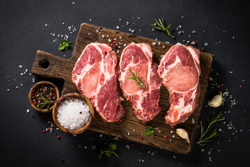 Pork meat at wooden board on black table.