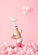 © GVS - Young pretty woman have fun with legs up lying in pink balloons over pink pastel background