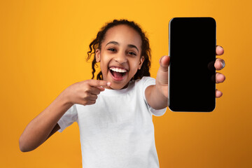Black girl showing blank empty smartphone screen and pointing