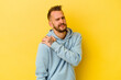 © Asier - Young tattooed caucasian man isolated on yellow background having a shoulder pain.