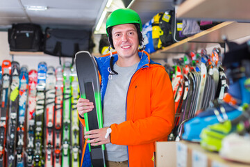 Wall Mural - Portrait of customer man in ski equipment who is standing with ski in sport store.