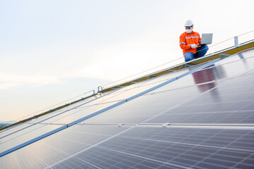 Wall Mural - Engineers use a laptop computer to examine the solar panels at a power plant installed with solar panels using solar energy..