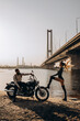 Romantic vacation of a biker and a girl on the river bank. Couple in love. Evening photo session.