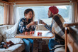 Couple sitting at a table in a motorhome and drinking tea.