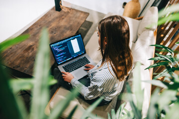 Young woman mobile developer with laptop, writes program code on a computer, programmer work in modern office.