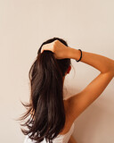 Fototapeta  - Vertical shot of a brunette woman making a ponytail