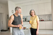 © insta_photos - Healthy sporty happy senior adults family couple drinking juice and laughing at home. Cheerful fit mid age older husband and wife enjoying talking, having fun standing in kitchen in the morning.