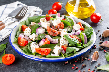 Wall Mural - Fresh vegetables salad from spinach, tomato, feta cheese, onion in plate on a dark background