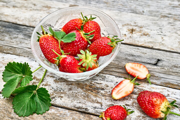 Wall Mural - Fresh red ripe organic bio strawberries in a bowl on wooden table in the garden. Spring or summer harvesting. Healthy eating. Vitamin.