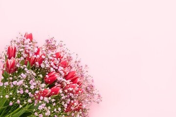 Pink tulips and gypsophila flowers bouquet on a pink background, selective focus. Mothers Day, birthday celebration concept