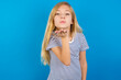 © Roquillo - Caucasian kid girl wearing striped shirt ​against blue wall  looking at the camera blowing a kiss with hand on air being lovely and sexy. Love expression.