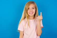 Caucasian Kid Girl Wearing Pink Shirt Against Blue Wall Shows Middle Finger Bad Sign Asks Not To Bother. Provocation And Rude Attitude.