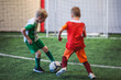 © tsuguliev - Football soccer game for kids, junior young football team group of children team having training session, or football game on a pitch, running and kicking ball on green pitch
