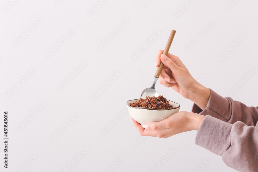Woman holding bowl with tasty quinoa on light background