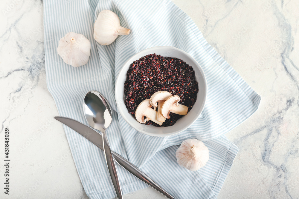 Bowl with tasty quinoa, mushrooms and garlic on light background