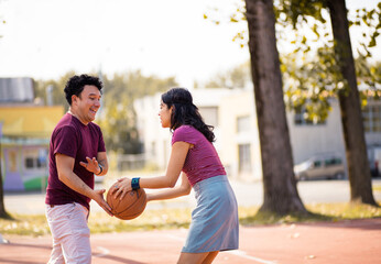 Young couple playing basketball on street court.