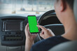 © photobuay - Mock up of man using mobile smart phone inside a car. Driver hand holding blank green screen smartphone, searching address and pin location via map navigator application, transportation