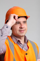 Wall Mural - portrait of successful young construction worker in hard hat on grey studio background greeting